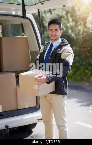 De notre entrepôt à votre porte. Portrait d'un liveur sympathique déchargeant des boîtes en carton de sa camionnette. Banque D'Images