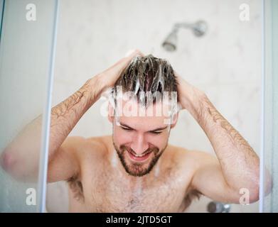 Shampooing et condition pour un cuir chevelu plus propre. Un beau jeune homme ayant une douche à la maison. Banque D'Images