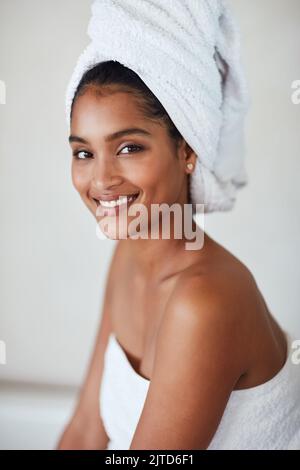 Votre bien-être vous vaut la peine. Portrait d'une jeune femme attrayante et détendue enveloppée dans une serviette à la maison. Banque D'Images