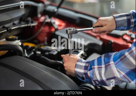 Mécanique automobile femelle en dévissant un écrou pour remplacer une bougie d'allumage de voiture. Banque D'Images
