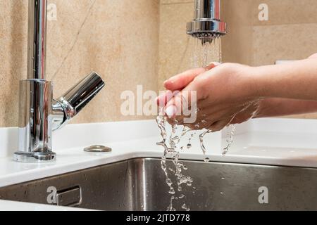 La fille lave ses mains sous des gouttes d'eau au-dessus de l'évier Banque D'Images