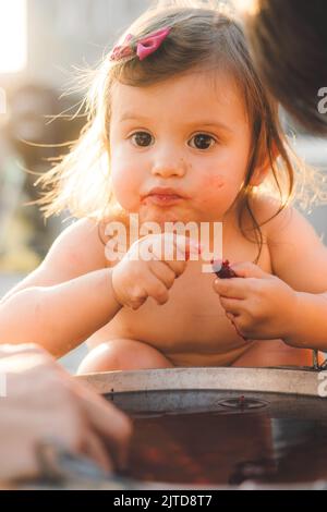 Petite fille de cueillette et de manger des cerises du bol plein de cerises qui ont besoin d'être lavées. Une alimentation saine. Garde d'enfants. Activité saine Banque D'Images