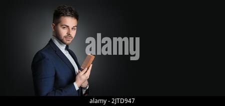Beau homme avec une coiffure élégante et un peigne sur fond sombre avec espace pour le texte Banque D'Images