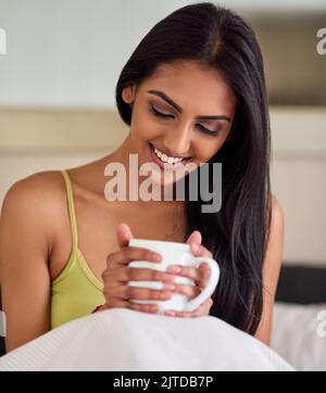 Je vous remercie d'avoir fait de mon jeu du matin un si fort. Une jeune femme heureuse appréciant son café du matin au lit. Banque D'Images