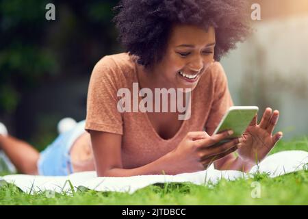 Le parc est l'endroit idéal pour un bon e-livre. Un jeune homme envoie des SMS tout en se relaxant dans le parc. Banque D'Images