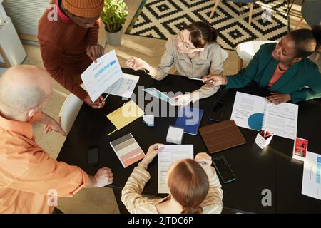 Vue de dessus lors d'une réunion d'équipe d'affaires créative au bureau, divers groupes de personnes assis à table Banque D'Images