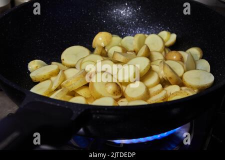 Les pommes de terre en tranches sont frites dans une poêle à gaz Banque D'Images