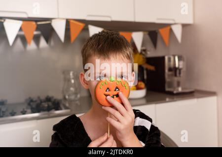 Portrait d'un petit garçon sur fond noir avec pain d'épice d'halloween Banque D'Images