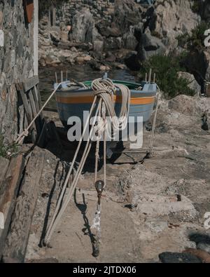 Une photo verticale d'un bateau sur une côte rocheuse à Scilla, en Italie Banque D'Images