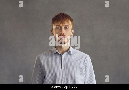Homme aux cheveux rouges sérieux tête de prise de vue studio visage portrait sur fond gris Banque D'Images