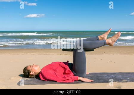 femme s'exerçant sur la plage avec l'anneau de pilates Banque D'Images