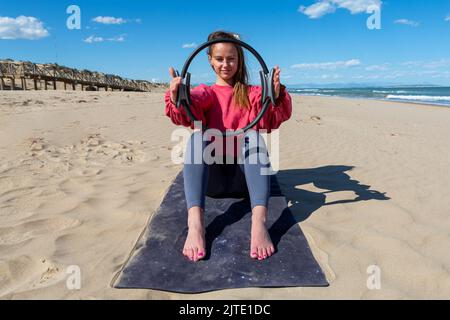 femme avec pilates anneau sur la plage Banque D'Images