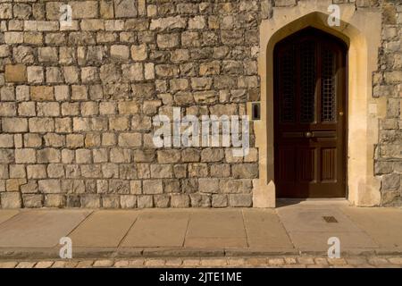 Détail gros plan de l'énorme mur de la tour du château médiéval en pierre avec porte en bois marron à utiliser comme arrière-plan Banque D'Images