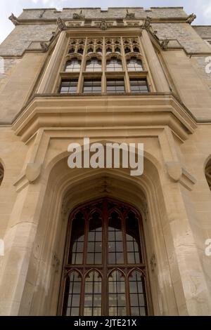 Vue de bas en haut d'une façade historique d'un château médiéval avec des arches pointues décorées porte de fenêtre et des remparts contre ciel partiellement nuageux Banque D'Images