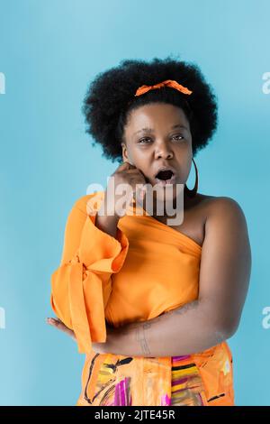 surprise african american corps positif femme isolée sur bleu, image de stock Banque D'Images