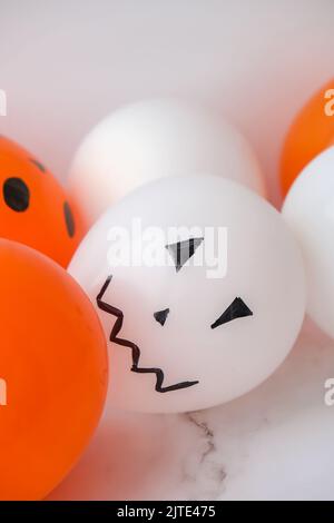 Les jacks peints font face aux ballons. Préparation des boules orange et blanches pour halloween. Activités à la maison pour Halloween. Jouets faits main Banque D'Images