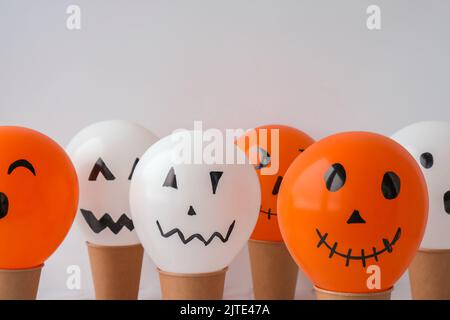 Les jacks peints font face aux ballons. Préparation des boules orange et blanches pour halloween. Activités à la maison pour Halloween. Jouets faits main Banque D'Images