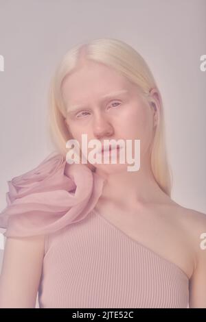 Portrait de la jeune fille albino avec cheveux longs blancs dans une élégante robe regardant l'appareil photo contre fond blanc Banque D'Images