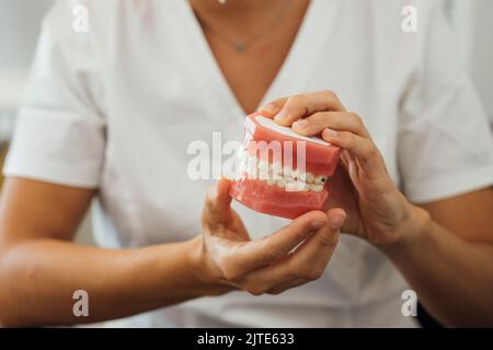 Vue partielle d'une infirmière tenant des prothèses dentaires entre les mains Banque D'Images