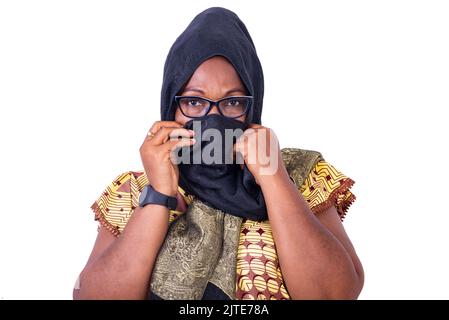 Portrait d'une femme musulmane mûre couvrant son nez avec son foulard noir. Banque D'Images