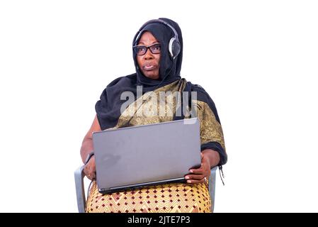 belle femme d'affaires musulmane assise sur fond blanc travaillant avec un ordinateur portable et un casque. Banque D'Images