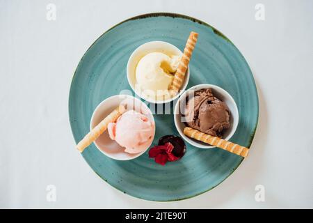 Vue de dessus de trois glaces dans des bols servis sur l'assiette bleue Banque D'Images