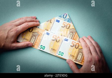 Concept de schéma pyramidal ou de schéma Ponzi. Euro argent plié comme forme de pyramide et homme montrant sur fond bleu, studio tourné. Banque D'Images