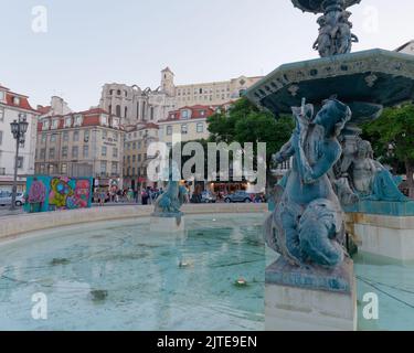 Fontaine et Mermaids sur la place Rossio une soirée d'été à Lisbonne avec l'église Carmo et les ruines du couvent en arrière-plan. Portugal Banque D'Images