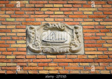 Ancien signe d'un navire en pierre sur un mur de briques à Bruges (Belgique) Banque D'Images