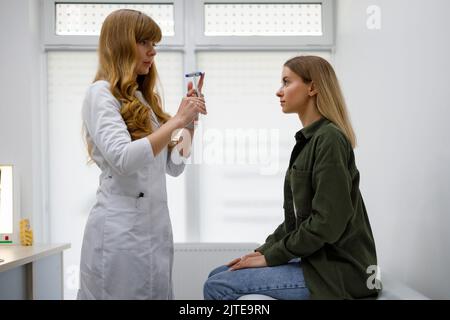 Médecin neurologue féminin inspectant le système nerveux de la patiente à l'aide d'un marteau. Examen physique neurologique Banque D'Images