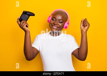 Photo de drôle funky fille utilisateur moderne dispositif de technologie lever les mains profiter de célébrer le succès atteindre isolé sur fond jaune de couleur Banque D'Images