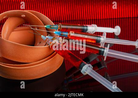 De nombreuses seringues remplies de liquide et de tourniquet torsadé. Concept d'injection de drogues. Banque D'Images