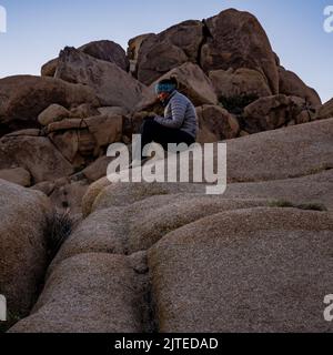 Femme dans Puffy Coat jouant au téléphone tout en attendant Sunrise dans le parc national de Joshua Tree Banque D'Images