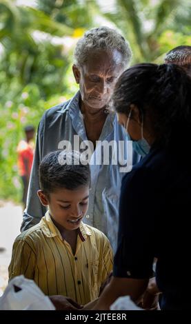 Enfant en attente de recevoir un colis alimentaire d'une communauté almsdonnant ardemment pieping: Galle, Sri Lanka 30th juillet 2022 Banque D'Images