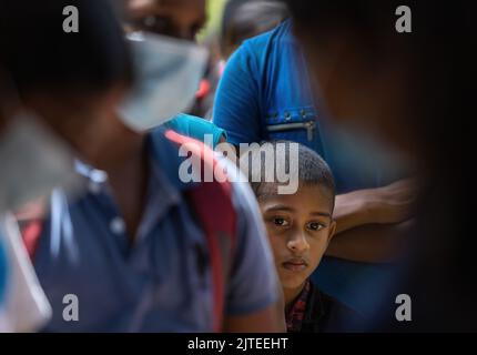 Enfant en attente de recevoir un colis alimentaire d'une communauté almsdonnant ardemment pieping: Galle, Sri Lanka 30th juillet 2022 Banque D'Images