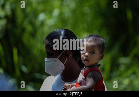 Enfant en attente de recevoir un colis de nourriture d'une communauté almsdonning ardemment: Galle, Sri Lanka 30th juillet 2022 Banque D'Images