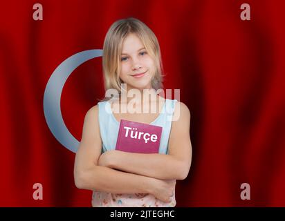 Jeune fille souriante et manuel avec inscription turc en langue turque sur fond de drapeau de Turquie Banque D'Images