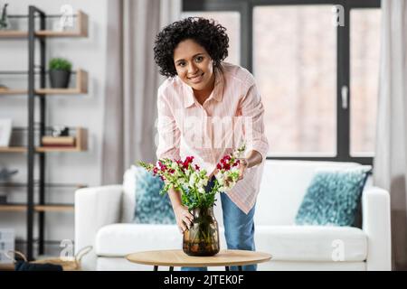 bonne femme plaçant des fleurs sur la table à la maison Banque D'Images