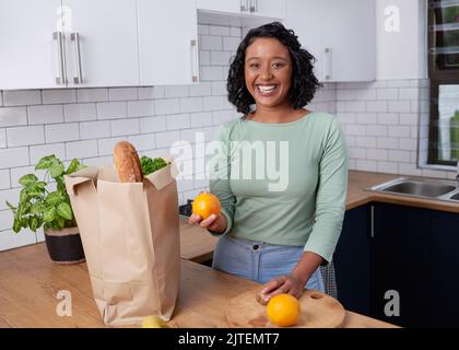 Une jeune femme multiraciale décompresse son épicerie dans la cuisine Banque D'Images