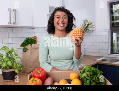 Une jeune femme végétalienne tient un ananas avec livraison de fruits et de boîtes de légumes Banque D'Images