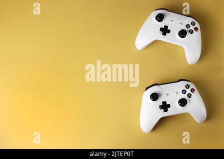 Deux gamepads de jeu sur le côté sur un fond jaune isolé Banque D'Images