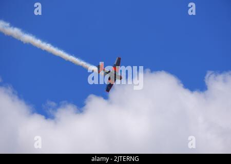 Petit avion à moteur unique faisant une manœuvre en boucle dans un ciel bleu ciel nuageux pour un spectacle aérien en été Banque D'Images