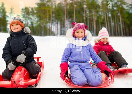 Heureux les petits enfants glisser vers le bas sur les traîneaux en hiver Banque D'Images