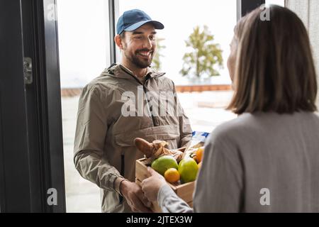 un liveur de nourriture donne la commande à une cliente Banque D'Images