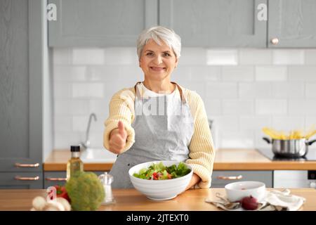 bonne femme qui prépare de la salade et qui montre ses pouces Banque D'Images