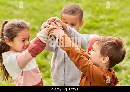 des enfants heureux jouant et se empilant les mains au parc Banque D'Images