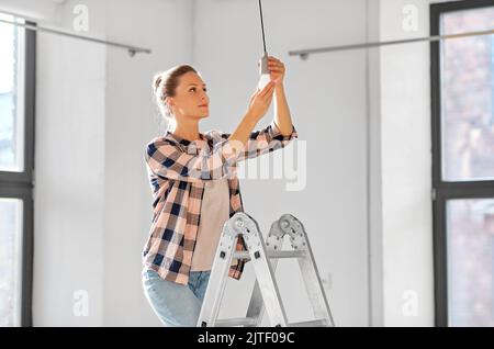 femme changeant d'ampoule chez elle Banque D'Images