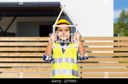 petite fille en casque avec règle en forme de maison Banque D'Images