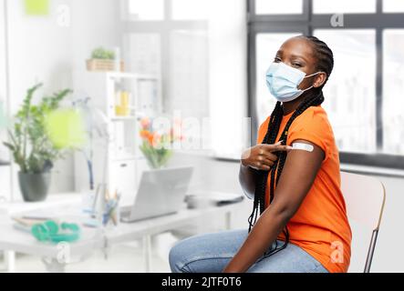 femme vaccinée en masque montrant un timbre sur l'épaule Banque D'Images