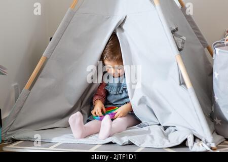 fille jouant avec le jouet de violon en tipi à la maison Banque D'Images